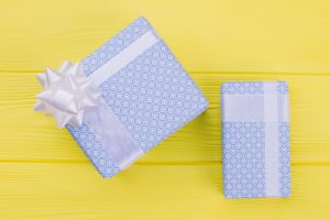 Blue gift boxes on yellow background. Present boxes packed in light blue patterned paper on color table. New Year or Christmas gifts.